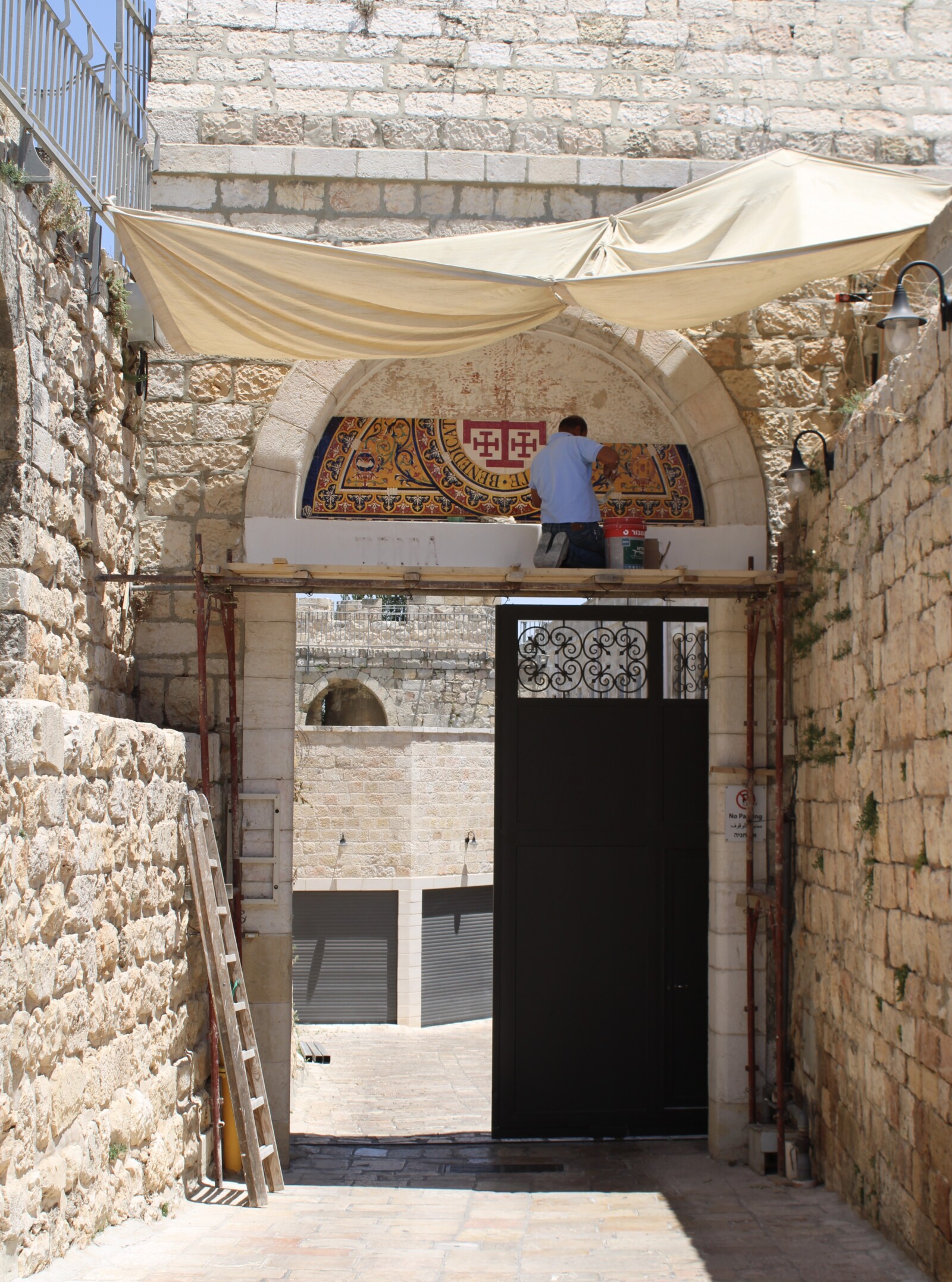 Ceramic panel being installed above the stone gateway of the Custody of the Holy Land.