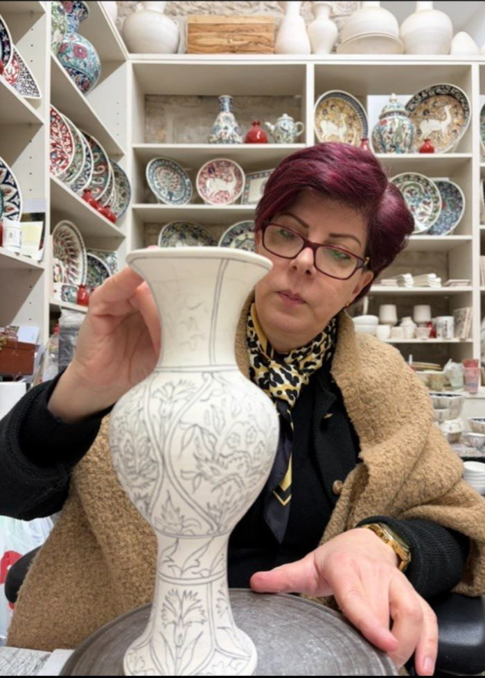 Dorin Sandrouni painting a ceramic piece